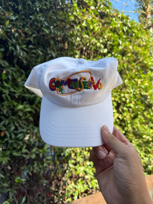 White cap with colorful logo held in front of green foliage