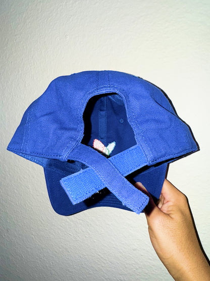 Back of dad hat with velcro adjustable held by a hand against a plain background